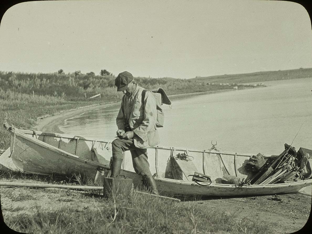 Lantern slide of Walter Rosene standing next to a boat